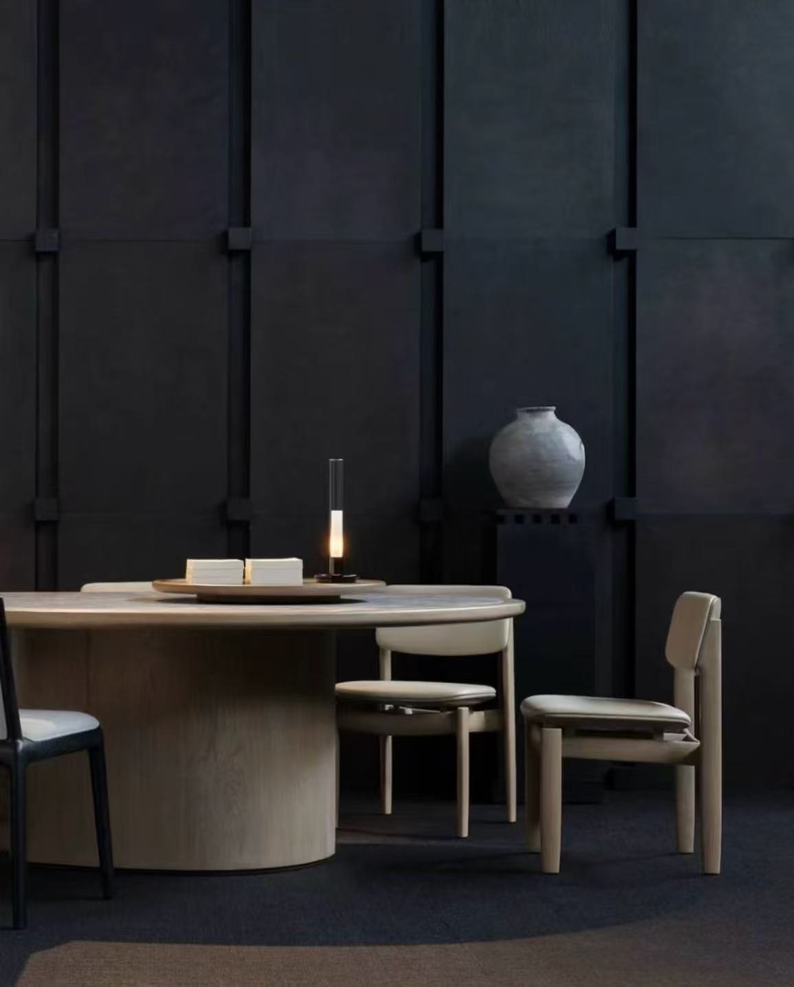 Modern minimalist dining room with light wood table, beige upholstered chairs, and dark geometric wall panels