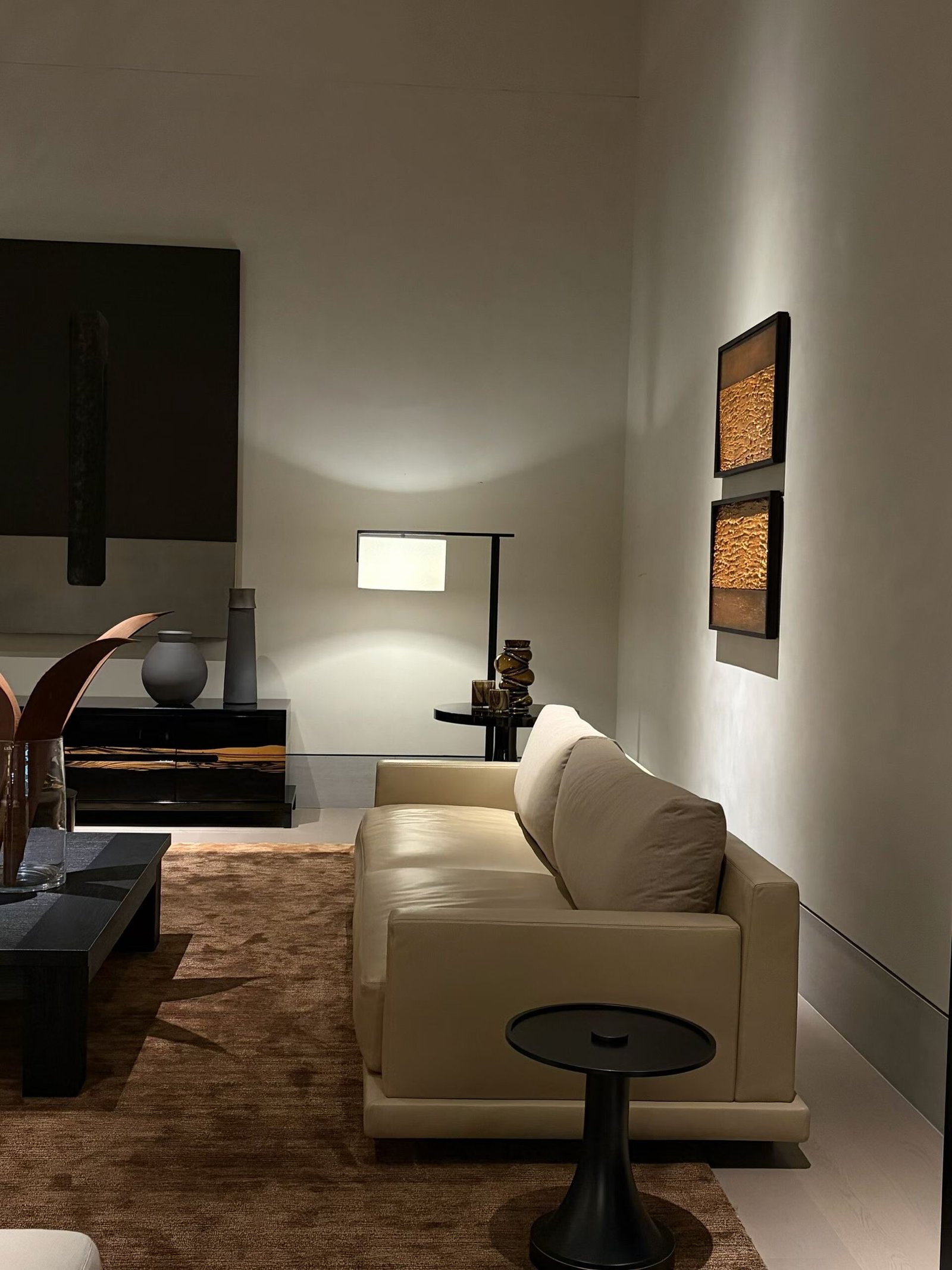 Modern luxury living room interior with beige leather sofa, textured rug, and glossy black cabinet with exotic wood inlay
