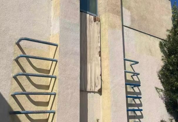 Peeling handrails and plywood-patched wall section on building facade — WUMEI survey